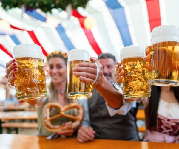 Group,Of,Friends,Celebrating,With,Beer,Mugs,In,An,Oktoberfest